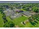 Aerial view of multiple outdoor tennis courts with manicured landscaping surrounded by lush trees and a community center nearby at 39653 Grove Hts, Lady Lake, FL 32159