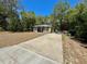 Exterior of house with vinyl siding, black shutters, and a long concrete driveway, surrounded by lush greenery at 40226 Palm St, Lady Lake, FL 32159