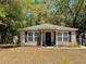 Exterior view showcasing vinyl siding, black shutters, and front porch, complemented by the natural landscape at 40226 Palm St, Lady Lake, FL 32159