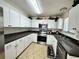 Well-lit kitchen featuring white cabinets, stainless steel appliances, and dark countertops at 40226 Palm St, Lady Lake, FL 32159
