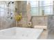 Close up on the soaking tub featuring tile accents, decorative seahorse and walk-in shower at 41522 Saddle Ridge Ln, Weirsdale, FL 32195