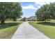 Long driveway leads to a traditional-style home with mature trees and landscaping, creating inviting curb appeal at 41522 Saddle Ridge Ln, Weirsdale, FL 32195