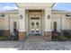 Elegant front entrance with stone accents, columns, and double doors, enhancing curb appeal at 41522 Saddle Ridge Ln, Weirsdale, FL 32195