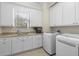 Well-organized laundry room with built-in cabinets, stainless sink, and modern washer and dryer at 41522 Saddle Ridge Ln, Weirsdale, FL 32195