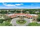 Aerial view of a large clubhouse with a terracotta roof and beautifully landscaped circular driveway at 4167 Capland Ave, Clermont, FL 34711