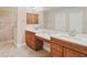 Bathroom with double sinks, white countertops, wood cabinets, tile floor, and tiled shower at 4320 Heritage Trl, Leesburg, FL 34748