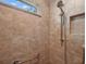 Walk-in shower with tan tiles, grab bar, window and shower head with wand at 4320 Heritage Trl, Leesburg, FL 34748