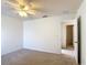 A bright, empty bedroom with carpeted floors, a ceiling fan, and an open doorway to another room at 4908 Cape Hatteras Dr, Clermont, FL 34714