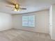 This bedroom features neutral carpet, a ceiling fan, and a window that allows natural light to fill the space at 4908 Cape Hatteras Dr, Clermont, FL 34714