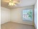 This bedroom features neutral carpet, a ceiling fan, and a window that allows natural light to fill the space at 4908 Cape Hatteras Dr, Clermont, FL 34714