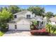 Beautiful white home with a three-car garage, lush landscaping, and manicured lawn at 4908 Cape Hatteras Dr, Clermont, FL 34714