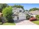 A white two-story home featuring a manicured lawn, a three-car garage, and colorful landscaping at 4908 Cape Hatteras Dr, Clermont, FL 34714