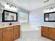 Bright bathroom features a soaking tub, dual vanities, and white tile flooring at 520 Rob Roy Dr, Clermont, FL 34711