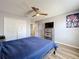 This bedroom has wood-look floors, a ceiling fan, a dresser, and a view into the bathroom at 520 Rob Roy Dr, Clermont, FL 34711