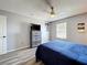 This bedroom has wood-look floors, a ceiling fan, a window for natural light, and a dresser with television at 520 Rob Roy Dr, Clermont, FL 34711