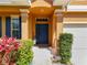 Inviting front entrance with a dark blue door, trimmed bushes, and manicured landscaping at 520 Rob Roy Dr, Clermont, FL 34711
