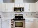 Contemporary kitchen with stainless steel appliances, herringbone backsplash, and bright, white cabinetry at 520 Rob Roy Dr, Clermont, FL 34711