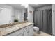 Bright bathroom features a granite double vanity, shower and a gray privacy curtain at 5890 Sw 83Rd St, Ocala, FL 34476