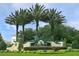Elegant community entrance sign with manicured landscaping and stately palm trees, showcasing a prestigious neighborhood at 6104 Hunters Ridge Ave, Leesburg, FL 34748