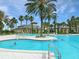 Inviting community pool with clear blue water, surrounded by lush palm trees and lounge chairs, perfect for relaxation at 6104 Hunters Ridge Ave, Leesburg, FL 34748