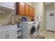 Bright laundry room features a white washer and dryer, sink, and wooden cabinets for storage at 6104 Hunters Ridge Ave, Leesburg, FL 34748