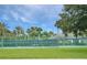 Outdoor tennis court with a fence, palm trees, and a well-maintained landscape under a bright, sunny sky at 6104 Hunters Ridge Ave, Leesburg, FL 34748