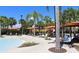 Community pool and lounge area featuring ample seating, sun umbrellas, and tropical landscaping at 8024 Oak Shadow Ct, Davenport, FL 33837