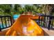 Close up view of water cascading down an orange water slide near tropical palm trees at 8024 Oak Shadow Ct, Davenport, FL 33837
