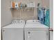 Functional laundry room with modern washer and dryer units and overhead shelving for storage at 8272 Procida Isle Ln, Windermere, FL 34786