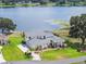 Beautiful lakefront home featuring a sprawling lawn, lush landscaping, and a serene lakeside setting at 1111 Myrtle Breezes Ct, Fruitland Park, FL 34731