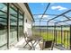 Enjoy tranquil water views on this screened balcony with a small table and chairs at 1111 Myrtle Breezes Ct, Fruitland Park, FL 34731