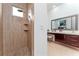 Bright bathroom features a stone-floored shower and vanity with wood cabinets and a large mirror at 1111 Myrtle Breezes Ct, Fruitland Park, FL 34731