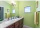Bathroom featuring green walls, large mirror, neutral tile, and ample counter space at 1111 Myrtle Breezes Ct, Fruitland Park, FL 34731