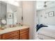 Bright bathroom boasts a wood vanity and mirror, with a peek into the adjacent bedroom at 1111 Myrtle Breezes Ct, Fruitland Park, FL 34731
