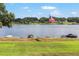 Picturesque lakeside view with a flag, seating, and lush green lawn leading to the calm water at 1111 Myrtle Breezes Ct, Fruitland Park, FL 34731