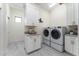 Bright laundry room with white cabinetry, granite counters, and modern appliances at 1111 Myrtle Breezes Ct, Fruitland Park, FL 34731