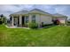 Back exterior view of home featuring a screened in lanai, manicured landscaping, and a lovely lawn at 1454 Neuport Path, The Villages, FL 32163