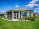 Back exterior view of home featuring a screened in lanai, manicured landscaping, and a well maintained lawn at 1454 Neuport Path, The Villages, FL 32163