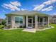 Back exterior view of home featuring a screened in lanai, manicured landscaping, and a lovely lawn at 1454 Neuport Path, The Villages, FL 32163