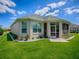 Back exterior view of home featuring a screened in lanai, manicured landscaping, and a well maintained lawn at 1454 Neuport Path, The Villages, FL 32163