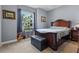 Cozy bedroom with a wooden bed frame, a large window with curtains, and light-grey walls at 16200 E Shirley Shores Rd, Tavares, FL 32778