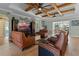 Spacious living room with exposed ceiling beams, comfortable leather seating, and a view of the lanai and pool at 16200 E Shirley Shores Rd, Tavares, FL 32778