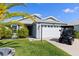 A well-maintained single-story home featuring a two-car garage and an adjacent golf cart at 1633 Manserra St, The Villages, FL 32163