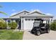 A single-story home featuring a two-car garage with a golf cart parked on the driveway at 1633 Manserra St, The Villages, FL 32163