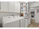 Well-equipped laundry room with modern washer and dryer, cabinetry, and a decorative shower curtain to the adjacent bathroom at 1633 Manserra St, The Villages, FL 32163