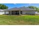 Private backyard with well-manicured lawn, covered patio and surrounding greenery at 16380 Se 84Th Ct, Summerfield, FL 34491