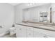 Bright bathroom featuring a double vanity with granite countertop, white cabinets, and a large mirror at 16380 Se 84Th Ct, Summerfield, FL 34491