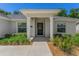 Covered front porch features decorative door, manicured bushes, and matching windows at 16380 Se 84Th Ct, Summerfield, FL 34491