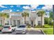 The front of the modern townhome features a stone facade, palm trees, and parking spaces at 17519 Hidden Forest Dr, Clermont, FL 34714