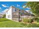 A rear exterior view of a home featuring a screened-in lanai and well-maintained lawn at 17519 Hidden Forest Dr, Clermont, FL 34714